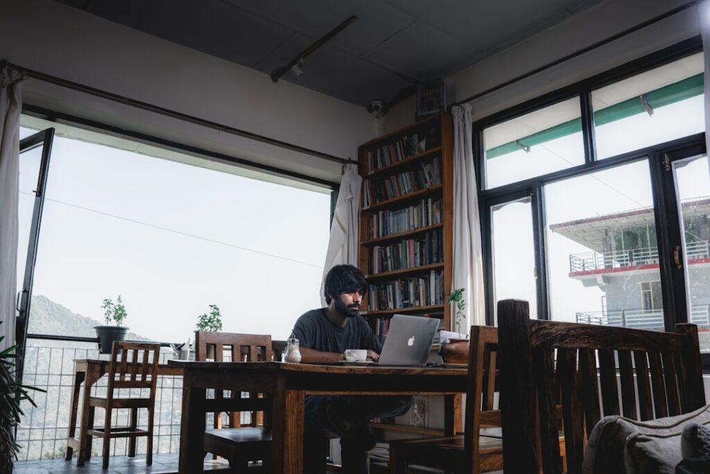 A man sitting at a table with a laptop, focused on analyzing AI enablement performance indicators and ROI.