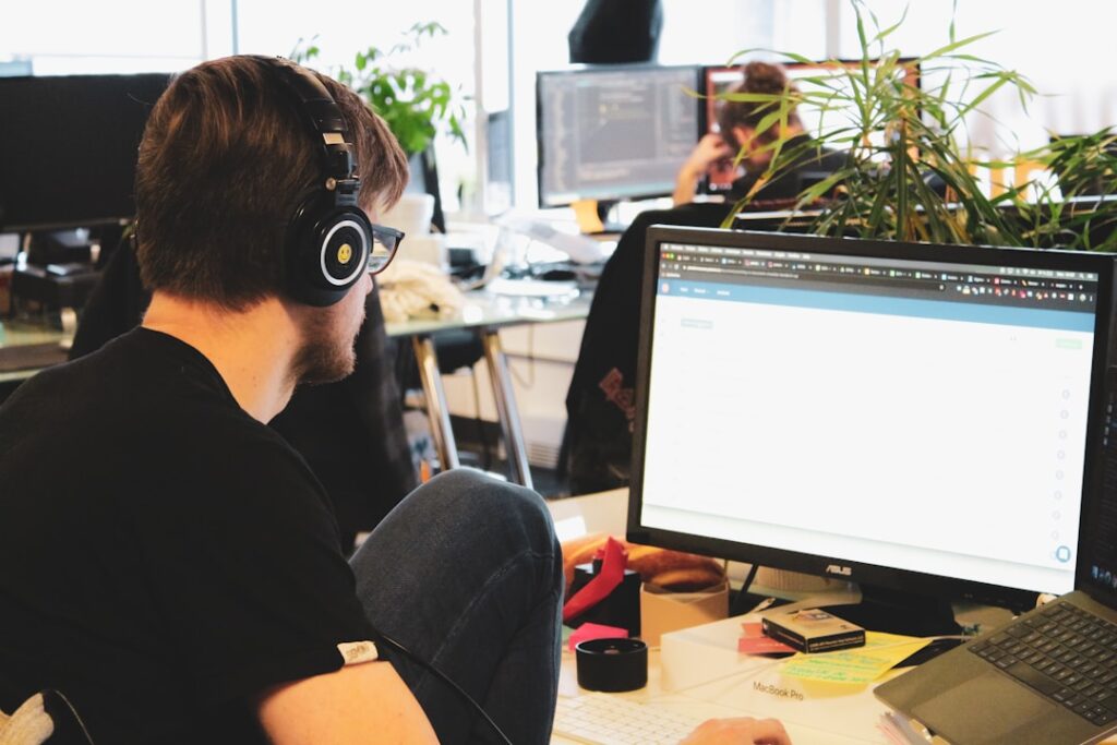 A male customer service representative working in a contact center, wearing a headset and providing digital customer service